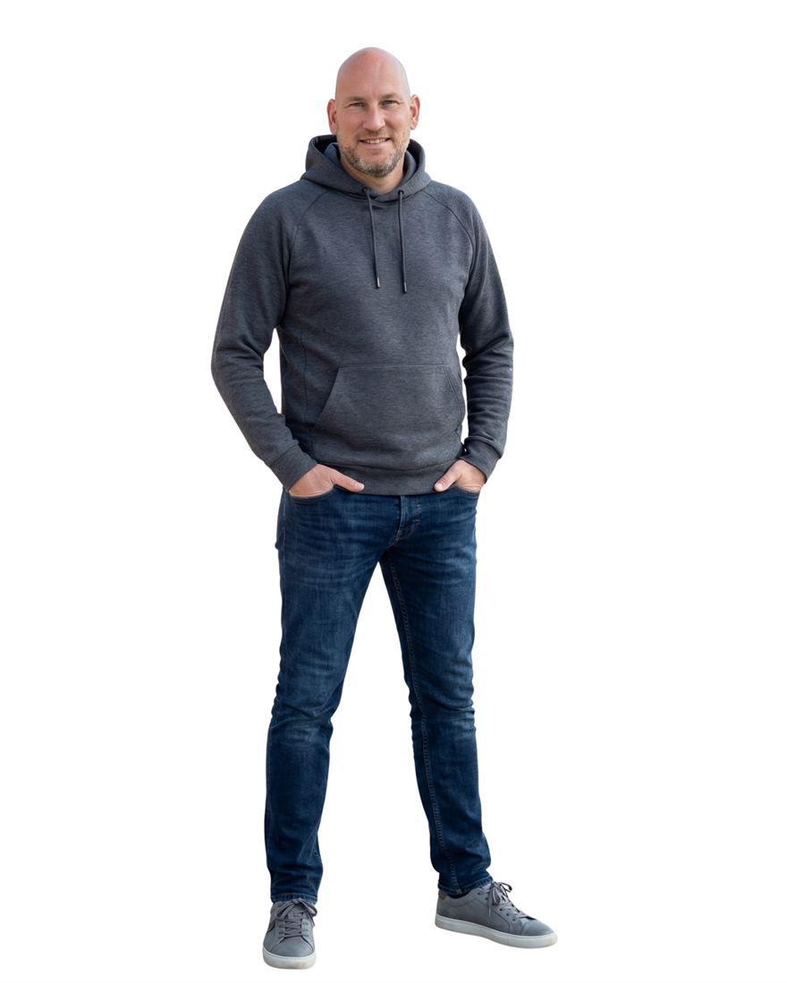 Alexander Amann, Psychologischer Berater, in grauem Hoodie und Jeans, lächelnd.